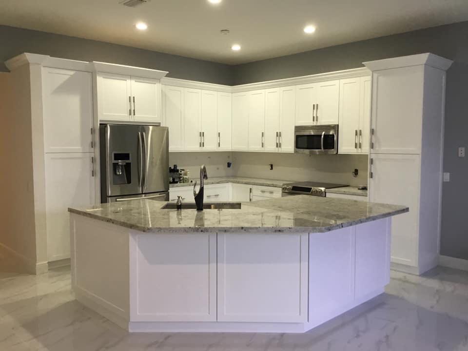 Finished kitchen with white shaker cabinets, granite island, and stainless steel appliances